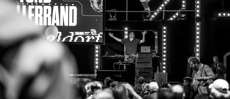 photo d'une foule de personne devant une scène ou un homme s'y tient debout